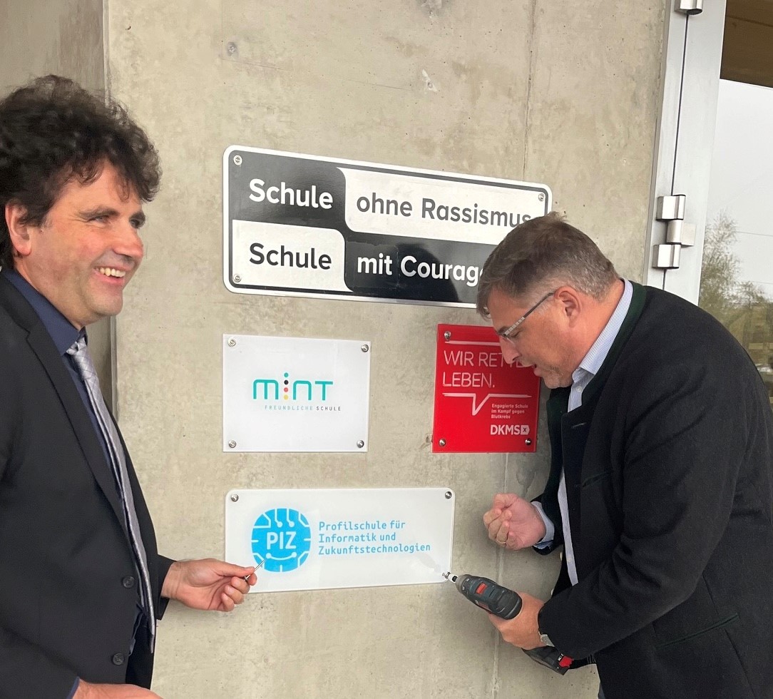 Landrat Stefan Löwl und Schulleiter des GMI Christoph Strödecke beim Anbringen der Auszeichnung Profilschule für Informatik und Zukunftstechnologien